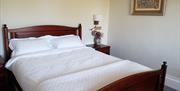 large double bed with bedside table, lamp and picture on the wall