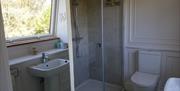 walk in shower, toilet nd wash basin with large window behind