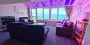 living area to relax in with a tv and a view of the beach