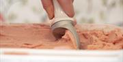 Strawberry ice cream being scooped from container.