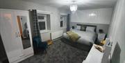 Carpeted double bedroom with a chair, wardrobe and a makeup table.