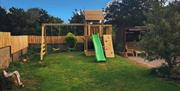 Back garden with outdoor playset with swings and a slide.