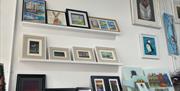 Art in picture frames displayed on shelves and wall