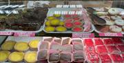 Shelf of baked treats including raspberry creams, cornflake squares and german biscuits