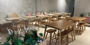 Wooden tables and seating benches in Blend and Brew with pastel cushions