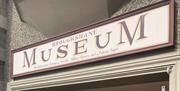 Red and Cream sign on building stating Broughshane Museum - Revolutionaries, Refugees, Royalty, Military Heroes and a Patron Saint.