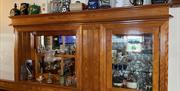 Wall mounted wooden and glass cabinet with range of collectible drinking items on display