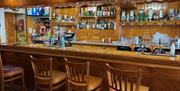 Bar area of Coast Road Inn with wooden bar seats and drinks on display