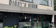 Grey, brown and green exterior of Digsy's Diner with green outdoor seating and plants