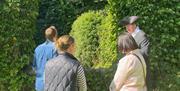Tour guide in period costume speaking to group of 3 people outside ruined church at Galgorm Castle.