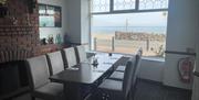 Table set up for group dining in Halfway House Hotel with brick fireplace in background and adjacent to window with sea views.