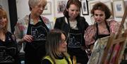 Audrey Kyle painting in her studio with workshop attendees watching on at Gobbins Studio , Islandmagee, Co Antrim