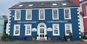 Blue Courtyard Shop building in Carrickfergus with white windoes and doors plus plants at the front