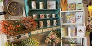 Table, shelf and cupboard display stands with range of items including pottery, books and artifical flowers