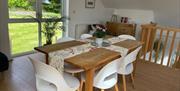 Wooden dining table with fabric runner and white seats in Loughview Lodge self catering