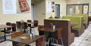 Wooden tables and seats, some with lime green backing within Lunchbox Cafe Larne