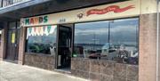 Exterior of Mauds Ice-Cream in Carrickfergus with brown tiles and MAUDS sign on cream banner