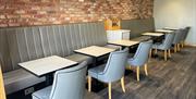 Red brick wall with grey seating and back benches with tables