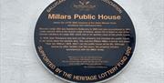 Wall mounted heritage plaque for Millars Public House detailing past owners and connections to James Orr.