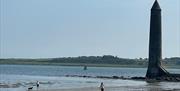 Chaine Memorial Tower with dog walkers on the adjacent beach.