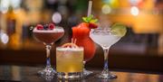 Four cocktails sitting on the bar in different shapes of glasses