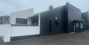 Black and white exterior of Ruby's Bar in Larne with sign featuring red name