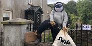 Robber scarecrow with Swag bag climbing over fence as part of Gracehill Scarecrow Competition