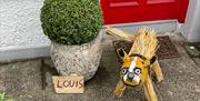 Straw dog called Louis leftng his leg to pee against a bush at Gracehill Scarecrow Competition