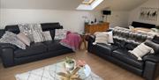 Living room sofa, brown leather with cushions and throws at Loughview Lodge. Glass coffee table with plant.