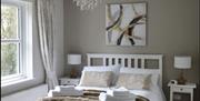 Reading corner in upstairs living room with oak dresser, lamp, throw, cushion, pouffe and selection of books.