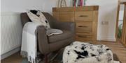 Reading corner in upstairs living room with oak dresser, lamp, throw, cushion, pouffe and selection of books.