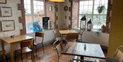 Interior of Season Coffee Shop with wooden flooring, wooden beams and wooden tables plus chairs.  Local artwork on display for sale.