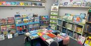 Children's corner in the Secret Bookshelf with books all around room and table with cushions and books in centre