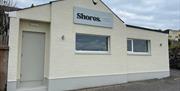 White exterior of Shores. Whitehead with windows facing onto Whitehead promenade.