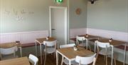 Green and white interior of Shores Whitehead, with wooden tables and white seats.