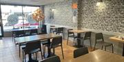 Interior of the Stove in Larne with wooden tables and grey decoration plus artifical red brick wall