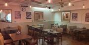 Interior of Taste Coffee Shop and restaurant with tiled floors, wooden tables and chairs with posters on walls