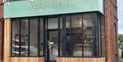 Exterior of Tweedie Pies Home Bakery with black framed glass, mint green sign and wooden panel trim