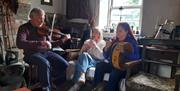Musicians playing traditional Irish instruments in a restored cottage