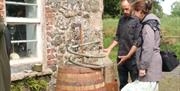 Two people discuss the workings of a poitin still outside a stone cottage