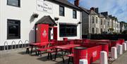 Exterior of Whitecliff Inn with red tables and chairs for seating area.