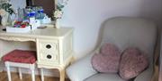 Vintage Room with a grey chair and two pink heart shaped cushions and a vintage dressing table with tea and coffee facilities.