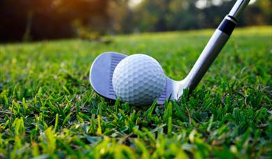 A golf club hitting a golf ball.