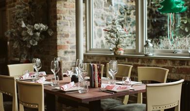 Corner view of a restaurant with frosty windows and a table set for a party of 8 guests to dine