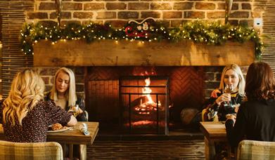 Guest dining in front of the fire surronded by Christmas decorations in Gillies Restaurant enjoying their Christmas Dinner