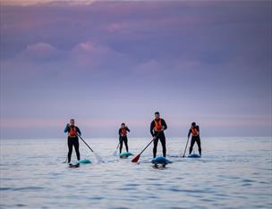 Group of paddleboarders in the open water with the flat horizon behind.