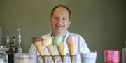 Man smiling standing in front of 4 different ice-creams.