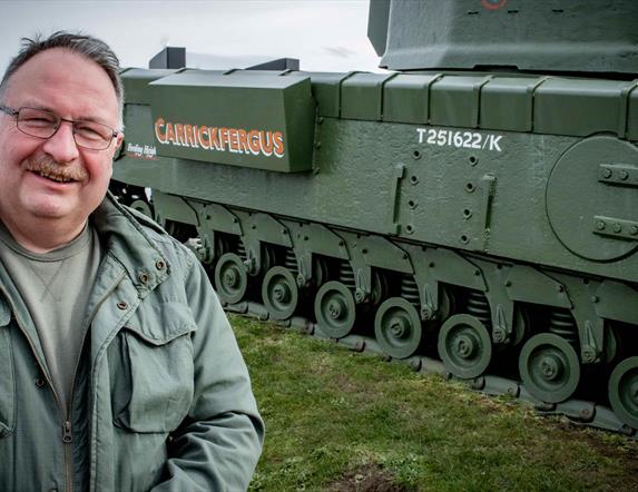 Adrian Hack, tour guide with Lead the Way Tours standing beside the Churchill Tank in Carrickfergus
