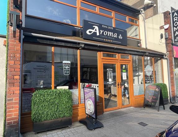 Exterior of Aroma Coffee Shop with wooden door entrance and external signs