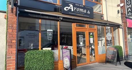 Exterior of Aroma Coffee Shop with wooden door entrance and external signs